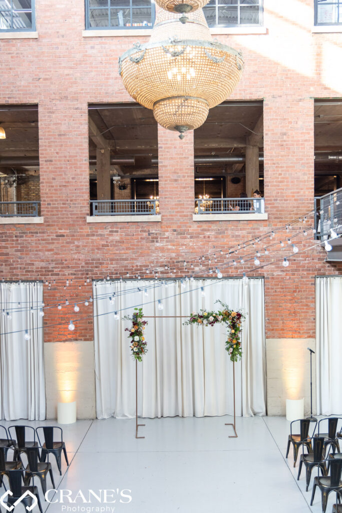 A lovely wedding ceremony site at the North Atrium of Artifact Events, which  is beautifully decorated with a metal arch that was overflowing with gorgeous flowers and string lights.