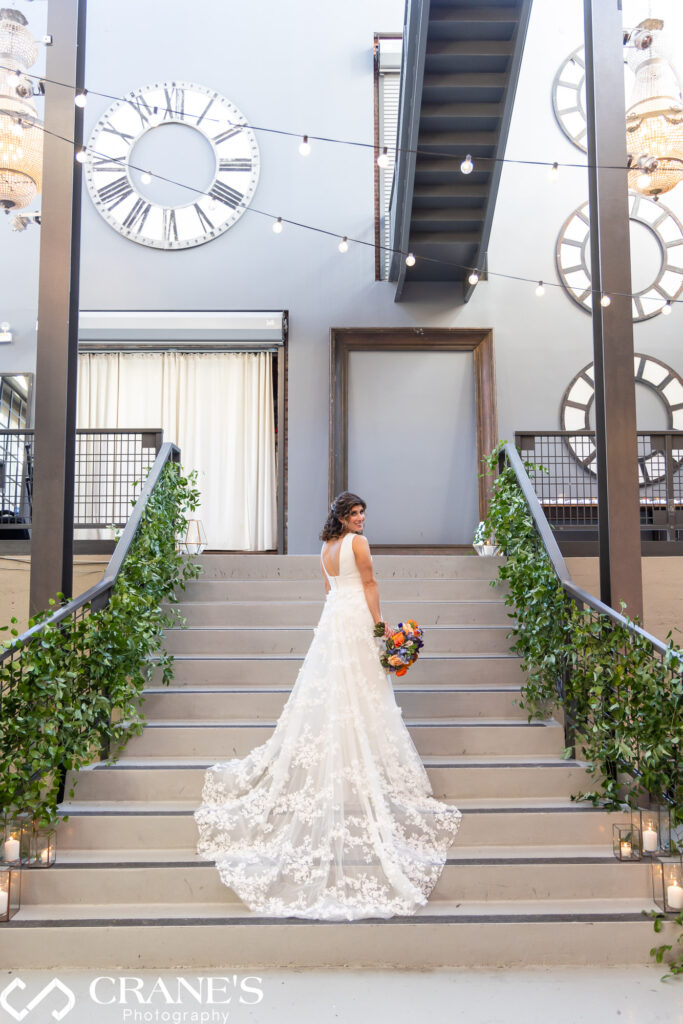Wedding portrait of a bride on the stairs at Artifact Events, beautifully decorated with greenery.