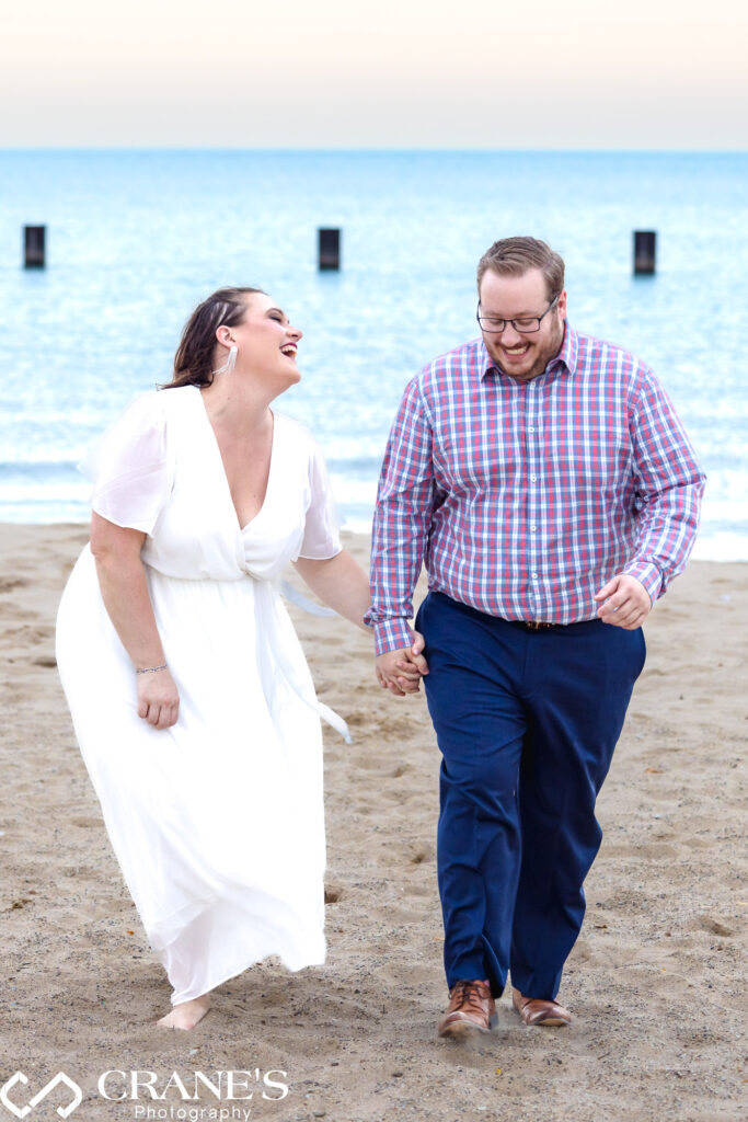 A joyous couple having fun while walking on the beach during their engagement session at Lincoln Park.