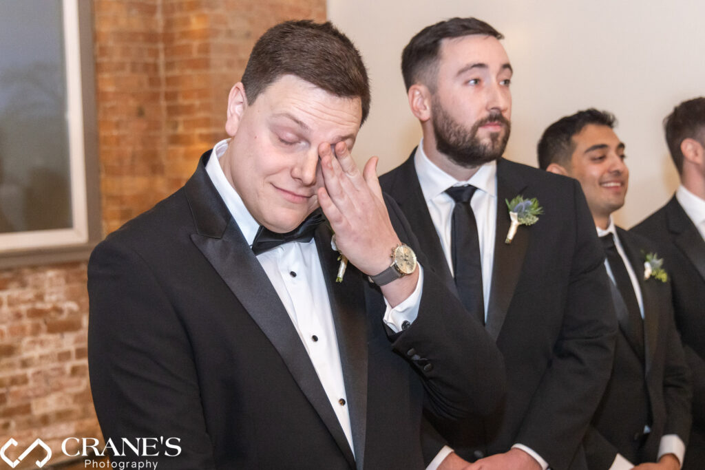 At City View Loft, the groom is moved to tears as he watches his bride and her dad walk down the aisle during their wedding ceremony.