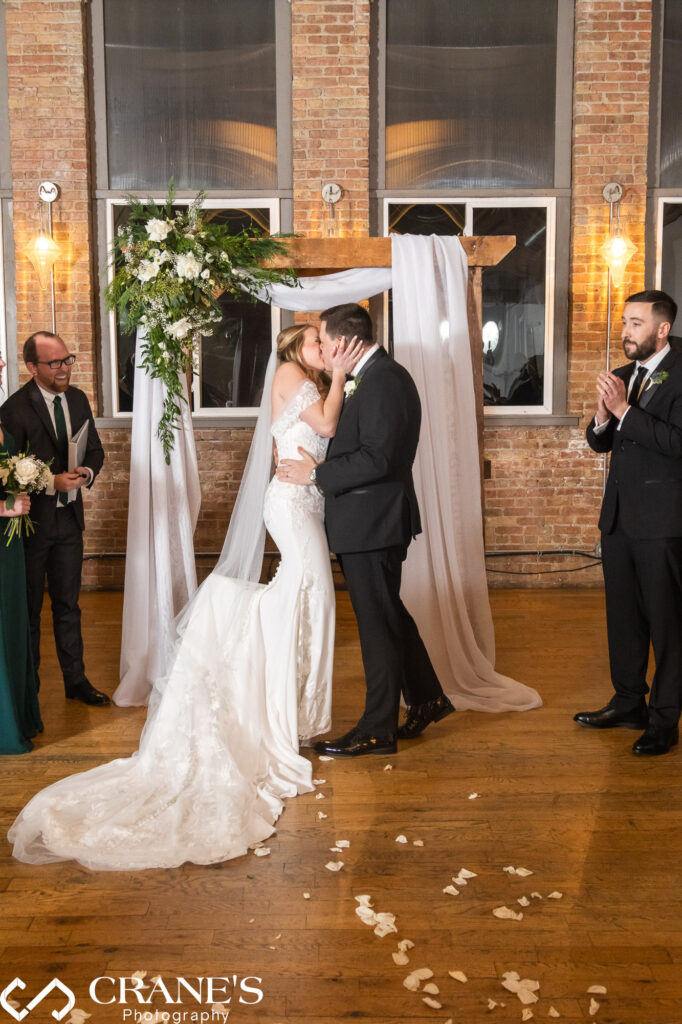 The sweet culmination of a beautiful wedding ceremony at City View Loft: the bride and groom share their first kiss as a married couple, surrounded by love and the promise of a new journey together.