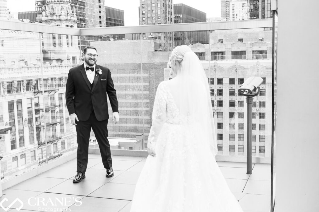 On the rooftop of the theWit Hotel in Chicago, the bride and groom share a poignant 'first look' moment, exchanging glances filled with emotion and anticipation just before their wedding ceremony begins.
