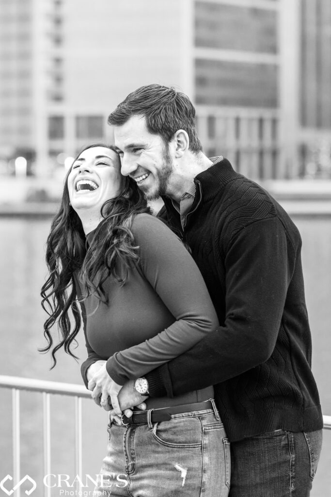 Amidst the winter beauty of Downtown Chicago, the engaged couple shares a joyful moment in their engagement photos. The girl laughs heartily while the guy embraces her warmly, capturing the essence of their love and happiness in the chilly setting.