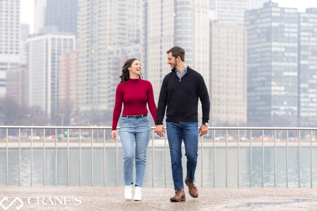 Hand in hand, this couple strolls through Downtown Chicago on a winter day, sharing laughter and joy during their engagement session at the iconic Olive Park