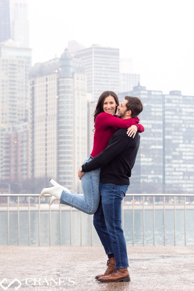 This casually dressed couple is capturing their engagement vibes in downtown Chicago on a winter day at Olive Park, creating laid-back and heartwarming memories against the city backdrop.