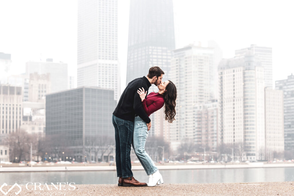 In their engagement session at Olive Park, the engaged couple shares a tender kiss against the stunning backdrop of Downtown Chicago's skyline, capturing a moment of pure romance and love.