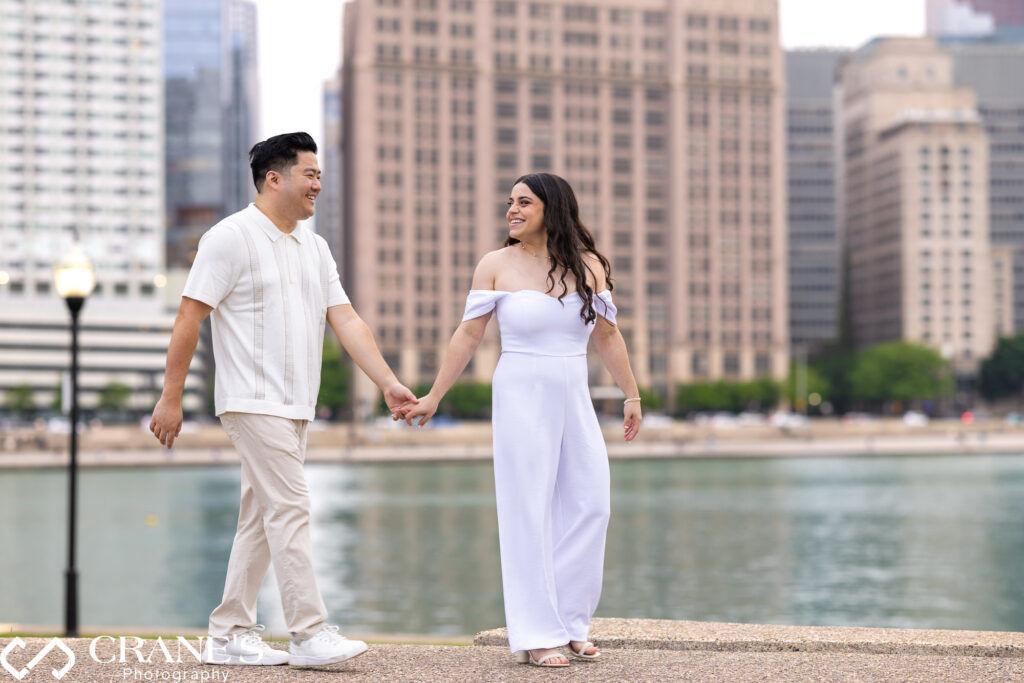 
A couple walks hand in hand through Olive Park during their engagement session, with the breathtaking skyline of downtown Chicago in the background.