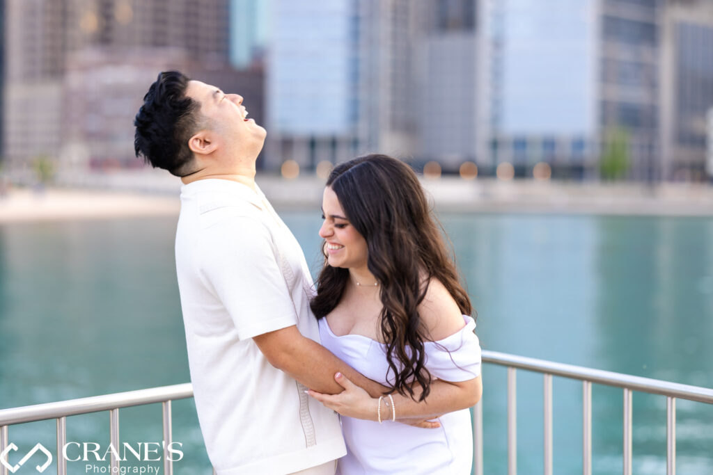 A couple laughing together while hugging at Olive Park, with downtown Chicago in the background. Their joyful expressions and close embrace highlight their happiness and love.