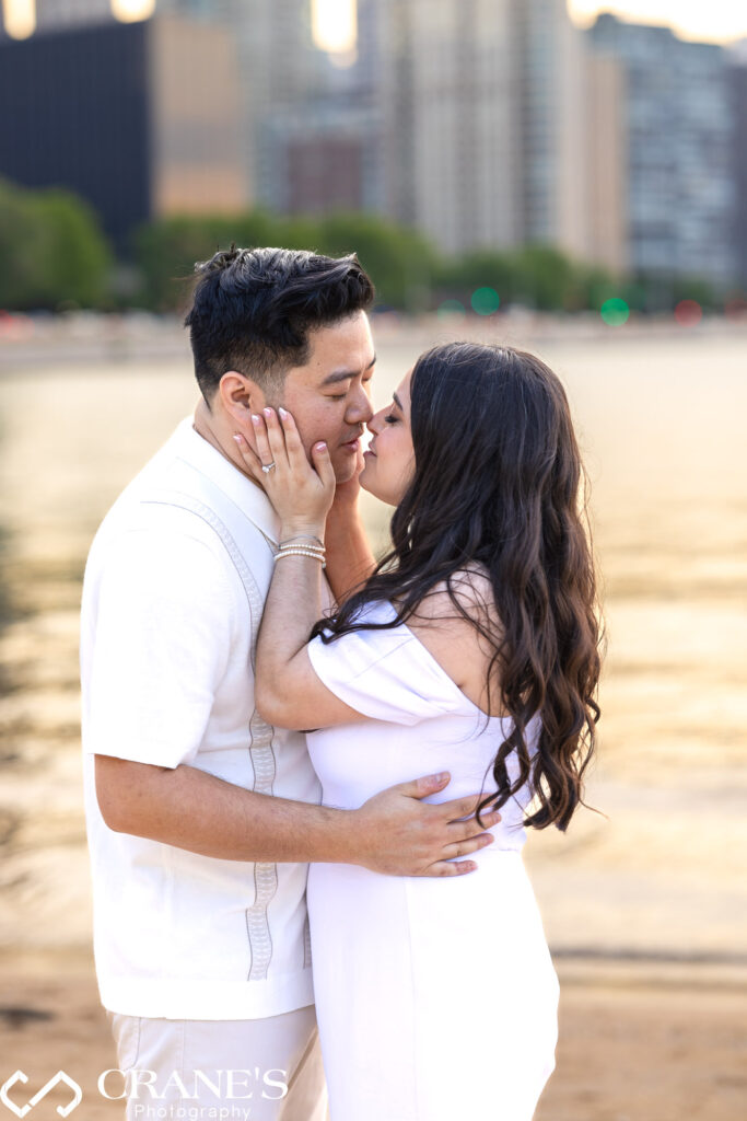 A romantic moment captured during an engagement session as a couple kisses at Olive Park during the golden hour. 