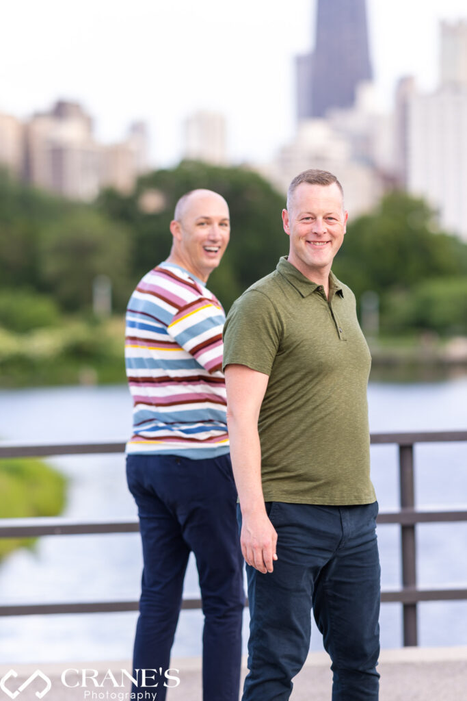 A jubilant LGBTQ+ couple, hands intertwined, stroll along the Chicago cityscape during their engagement session, their faces beaming with happiness.