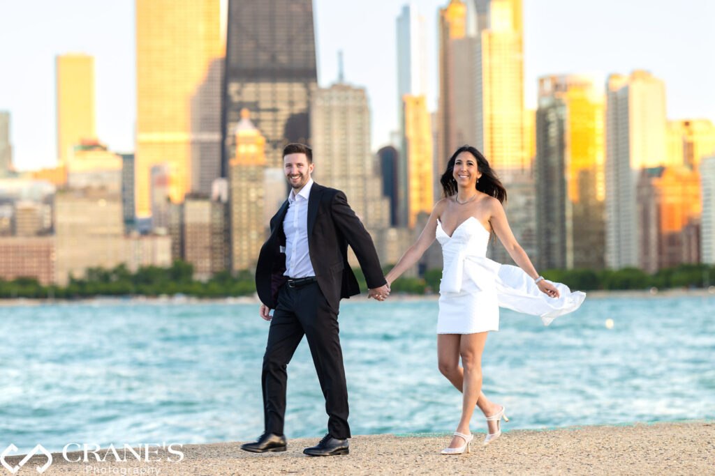 An award-worthy portrayal of love. Elegantly dressed on the shores of North Avenue Beach, a couple shares a moment of pure joy and connection, their engagement a promise etched in the golden light.