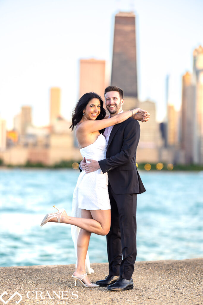 An elegantly attired couple shares a romantic moment on North Avenue Beach during the golden hour. The soft, golden light creates a magical backdrop for their engagement photo.