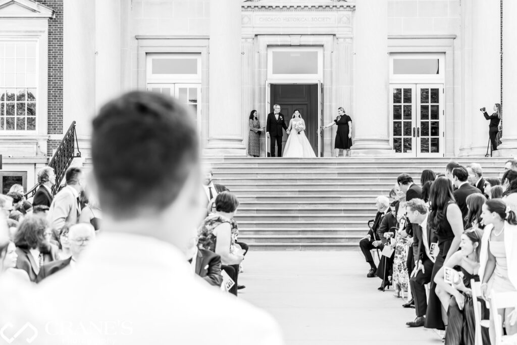 Chicago History Museum wedding: Groom's first look as bride descends grand staircase. Breathtaking architecture frames the timeless moment.