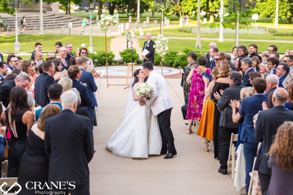 Newlyweds share a kiss down the aisle after being pronounced husband and wife at a Chicago History Museum wedding ceremony.