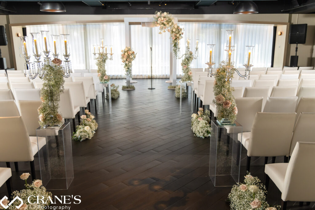 A black-tie wedding ceremony setup at RPM Events showcasing elegant white chairs arranged for guests. At the center, a beautifully decorated Chuppah adorned with delicate flowers creates a romantic and inviting focal point for the ceremony.