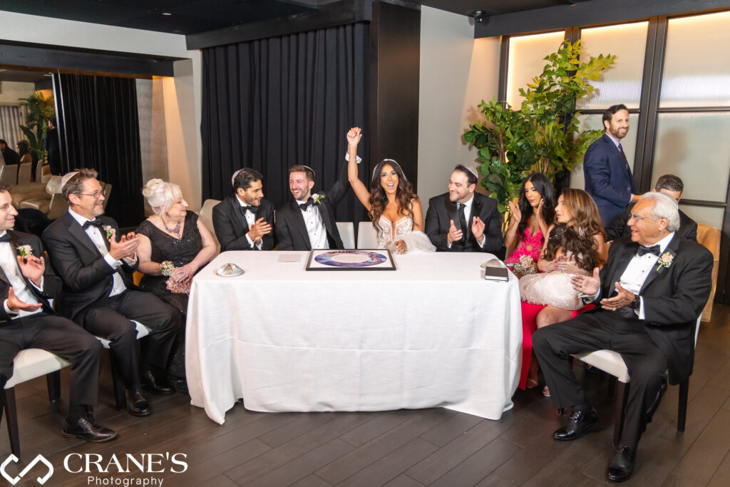 A Jewish wedding ceremony at RPM Events in Chicago, capturing the significant moment of signing the ketubah. The image highlights the couple and their witnesses engaged in this important tradition, with the elegant venue setting providing a beautiful backdrop for a black-tie event.