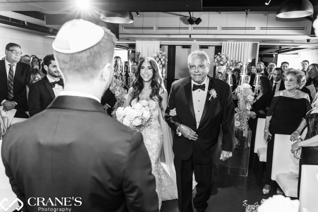 A touching moment from a Jewish wedding ceremony at RPM Events, where the bride and her father walk down the aisle.