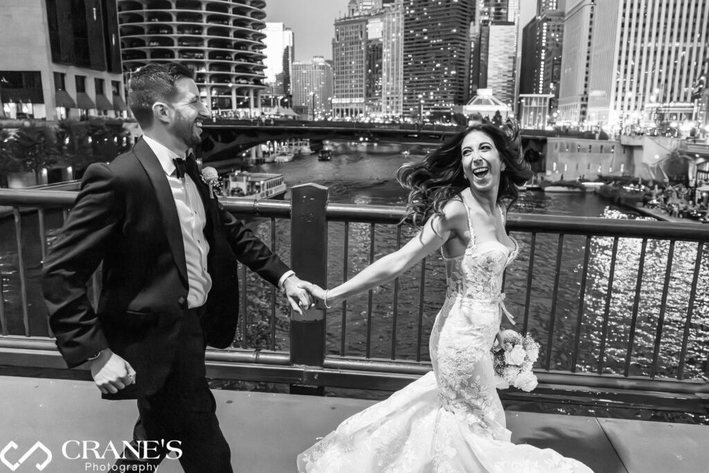 A candid wedding photo of the bride and groom running joyfully at Clark Street Bridge at night, just outside RPM Events. 