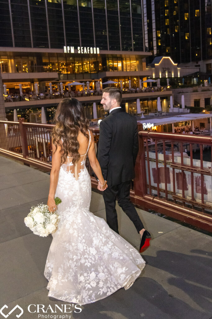 A stunning black-tie wedding at RPM Events in Chicago, featuring the stylish bride and groom posing against the venue’s elegant backdrop. The image captures them at the Clark Street Bridge at night, with the city lights adding a magical touch to their glamorous celebration.