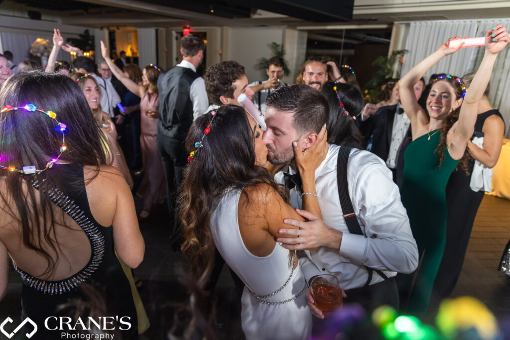 The bride and groom share a romantic kiss on the dance floor at their wedding reception at RPM Events. The moment captures their love and affection, set against the backdrop of their black-tie celebration.