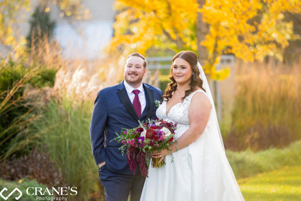 Bride and groom posing for a fall wedding photo, with the vibrant yellow leaves of autumn trees creating a stunning backdrop at the Morton Arboretum.