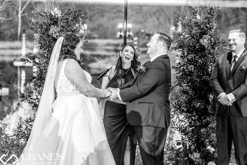 During the vows at the Ginkgo Room wedding ceremony, David’s twin sister, who officiated, sneaks in a playful joke, causing both the bride and groom to laugh joyfully in the midst of their heartfelt moment.