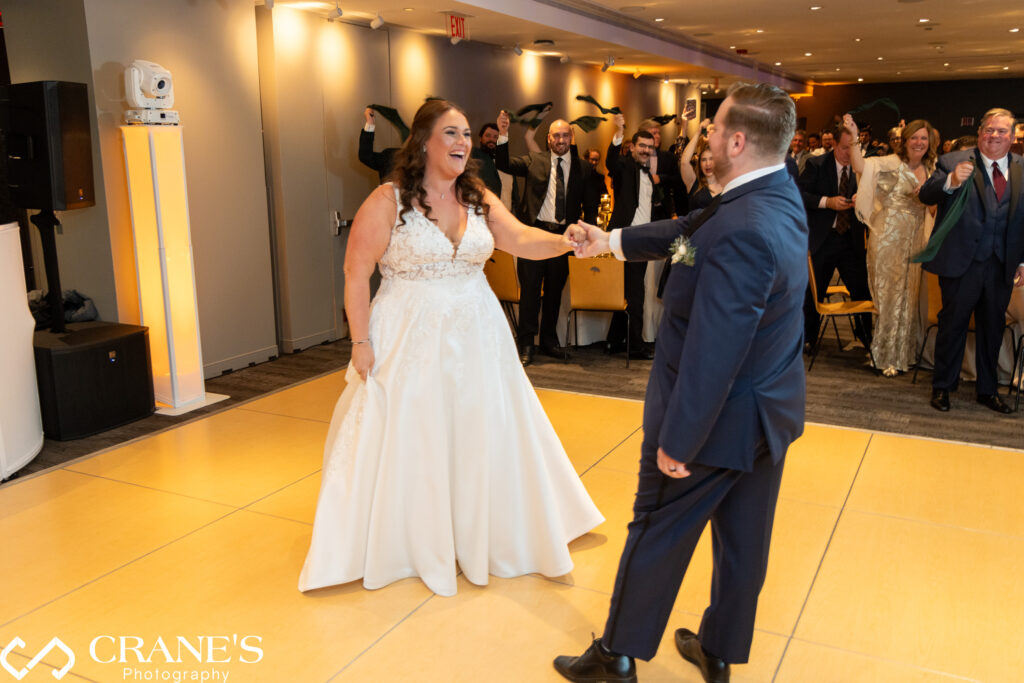 Julia and David sharing their first dance as a married couple, surrounded by friends and family in the warmly lit Ginkgo Room