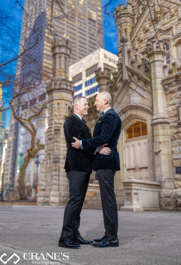 A same-sex wedding couple poses in front of the historic Chicago Water Tower, captured in a timeless matter by award-winning Chicago wedding photography studio, Crane’s Photography.