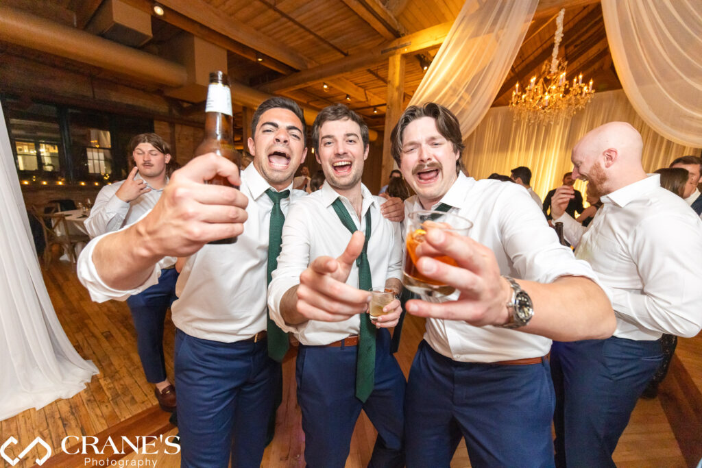 Groomsmen dancing and celebrating on the dance floor during a lively wedding reception at the Skyline Loft at Bridgeport Art Center.
