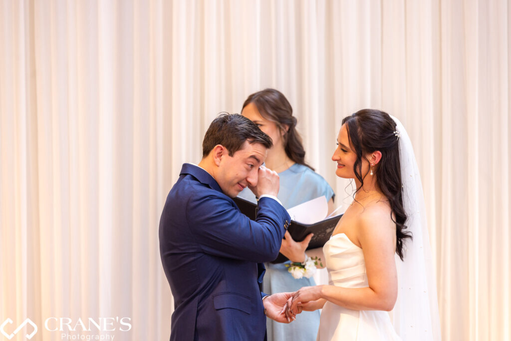 Groom wiping tears during emotional vow exchange at wedding ceremony in the Skyline Loft.
